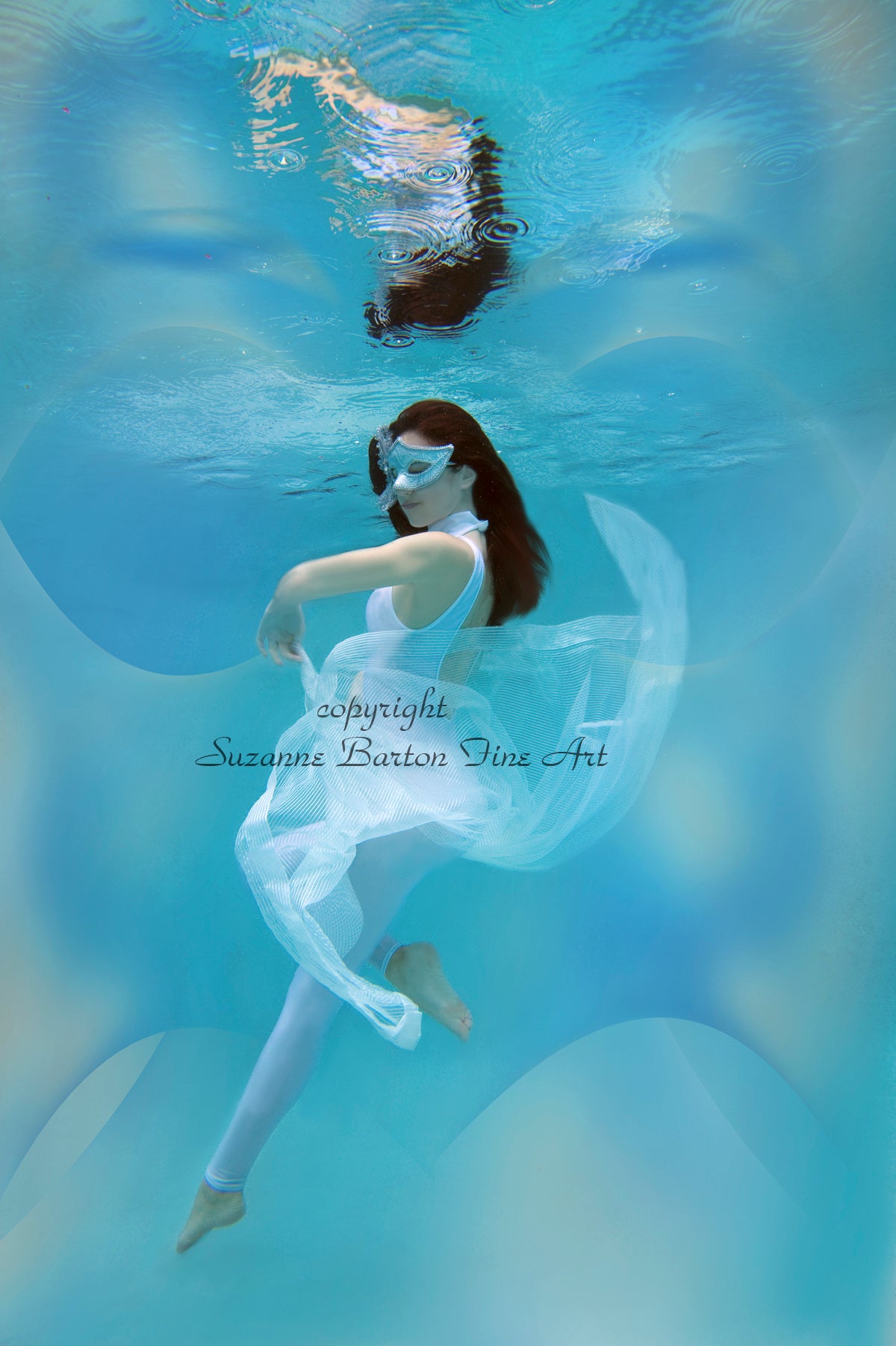 A woman gracefully submerged underwater wearing a beautiful white mask and surrounded by flowing white tulle fabric.