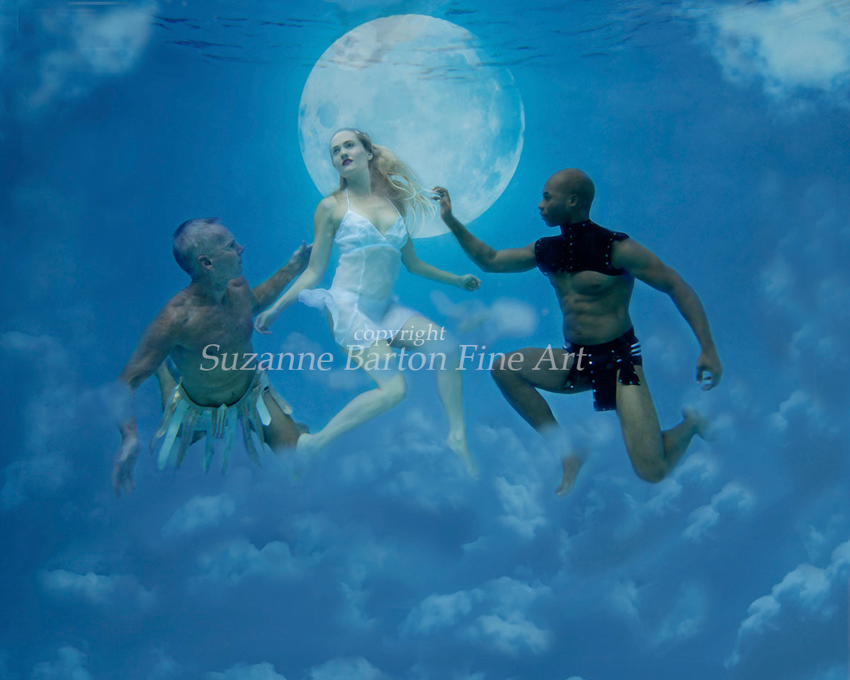 Mythical looking underwater image of a woman in white flocked by two shirtless men with a gladiator feel. Weightless and floating, a full moon and clouds appear behind them.