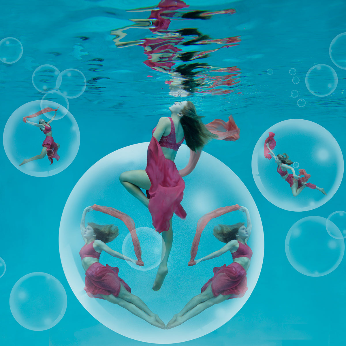 Five beautiful women positioned artfully in large whimsical bubbles underwater. Pink scarves float elegantly with the women.